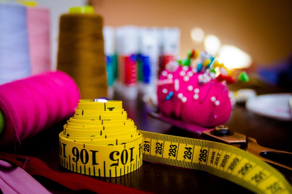 Fashion Studio Equipment: Measuring tape with pin cushion and thread in the background