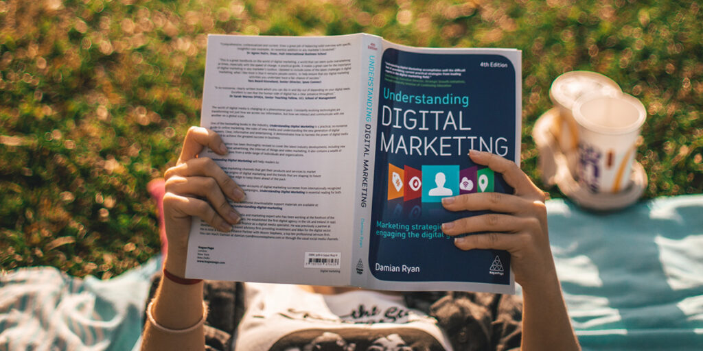 Person reading book titled 'Understanding Digital Marketing'