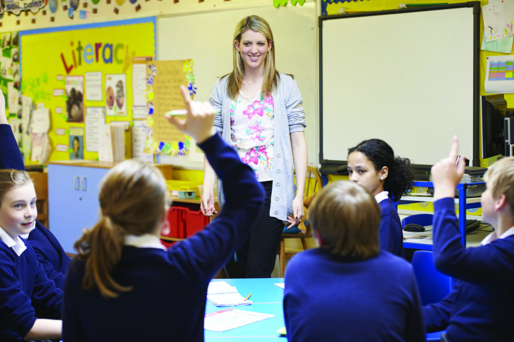 A teaching assistant talking to primary school students