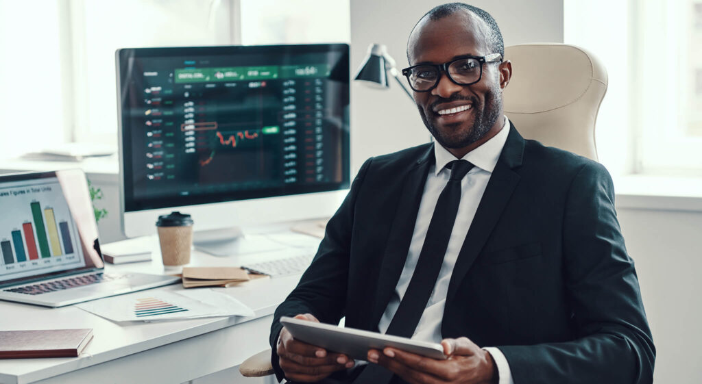 Compliance and Risk professional, Man sits in front of computer with trading and financial data on it.